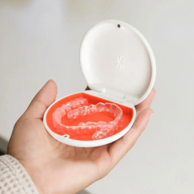 Adulto sorrindo com alinhadores Invisalign durante o tratamento ortodôntico